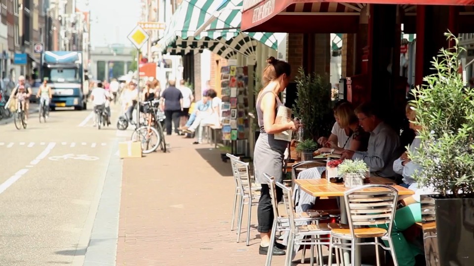 A Rua Haarlemmerdijk em Amsterdã é exemplo de um bom espaço urbano ao nível dos olhos. Tem equilíbrio entre a presença de carros, bicicletas e pedestres e os térreos dos imóveis tem funções diversas e abertas à via, que convidam os pedestres a entrar. | Reprodução/