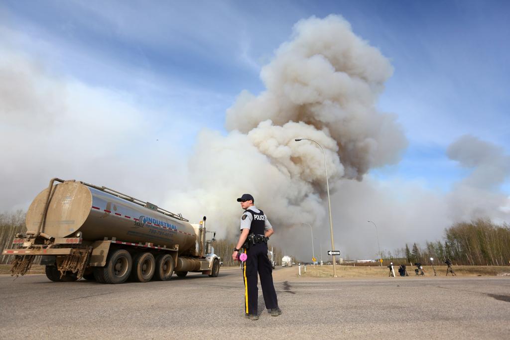 Policiais têm formado comboios para evacuar moradores da região de Fort McMurray | COLE BURSTON//AFP
