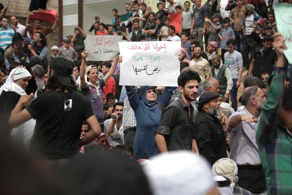 Mulher segura cartaz em manifestação em Aleppo, pedindo para todos os rebeldes terminarem as lutas e pararem com as mortes na cidade | ABDULMONAM EASSA/AFP
