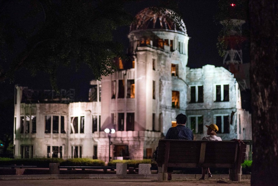 Um casal senta em um banco na frente do Memorial da Paz de Hiroshima: Obama estará na cidade nesta sexta-feira (27) | JOHANNES EISELE/AFP