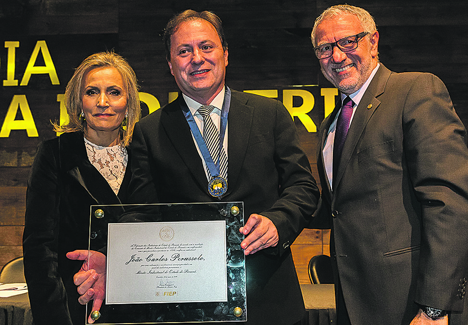 O empresário João Carlos Perussolo, ao lado da mulher, Sonia, e do presidente da Federação das Indústrias do Paraná, Edson Luiz Campagnolo, que lhe entregou a medalha do Mérito Industrial na cerimônia pelo Dia da Indústria. | Fred Kendi