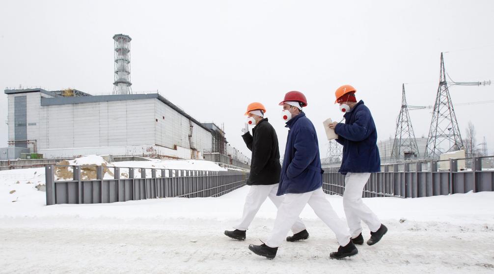 Visitantes caminham em frente ao quarto reator danificado da usina de Tchernóbil | Gleb Garanich/AP