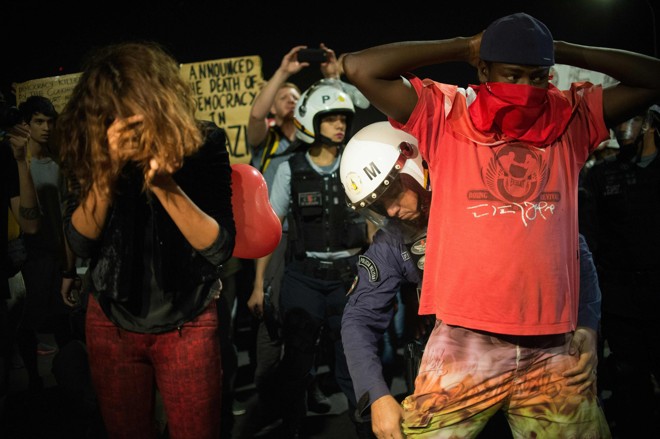 Jovens são revistados pela polícia durante manifestação contrária ao impeachment, em Brasília. | Andressa Anholete/AFP