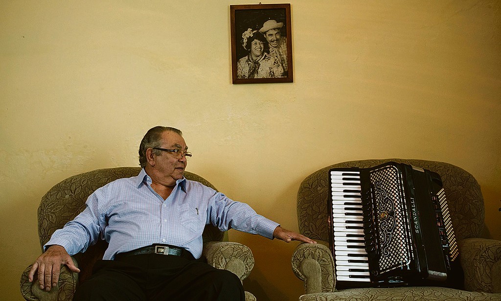 Ivan Graciano com a antiga gaita do pai: memória resgatada. No alto, na parede, uma foto de Gabriela e Belarmino