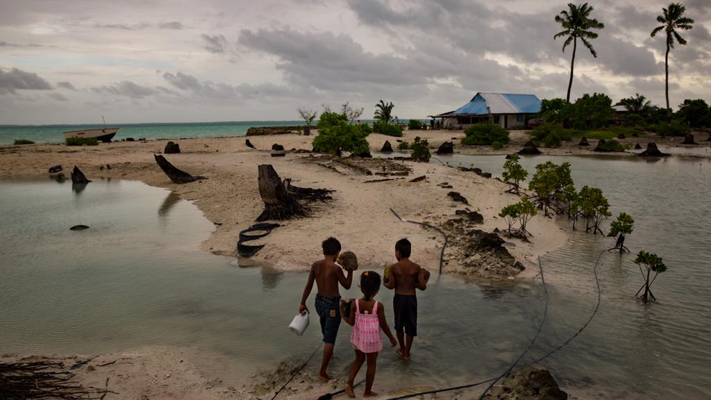 Crianças voltam para casa na vila de Abarao: Kiribati planeja “migração com dignidade” dos seus moradores para uma ilha em melhor situação | Josh Haner/ The New York Times