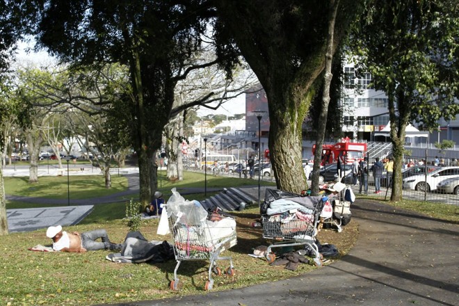 Moradores de rua alheios ao comboio da tocha na Praça Afonso Botelho, em frente à Arena. | Daniel Castellano/Gazeta do Povo
