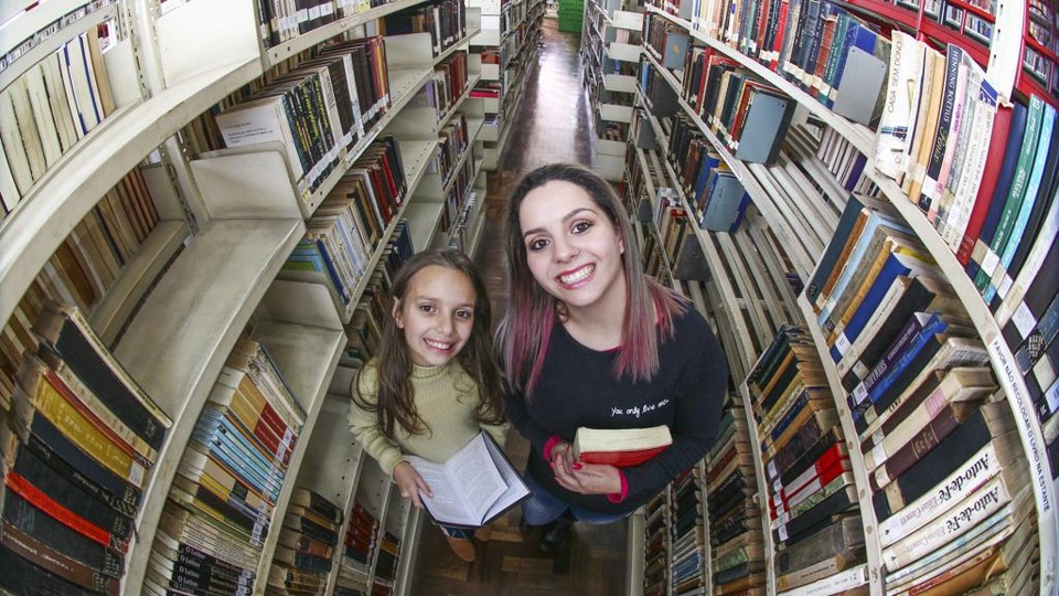 As irmãs Sabrina (mais nova) e Kathleen escolhem livros na Biblioteca Pública. | Daniel Castellano/Gazeta do Povo