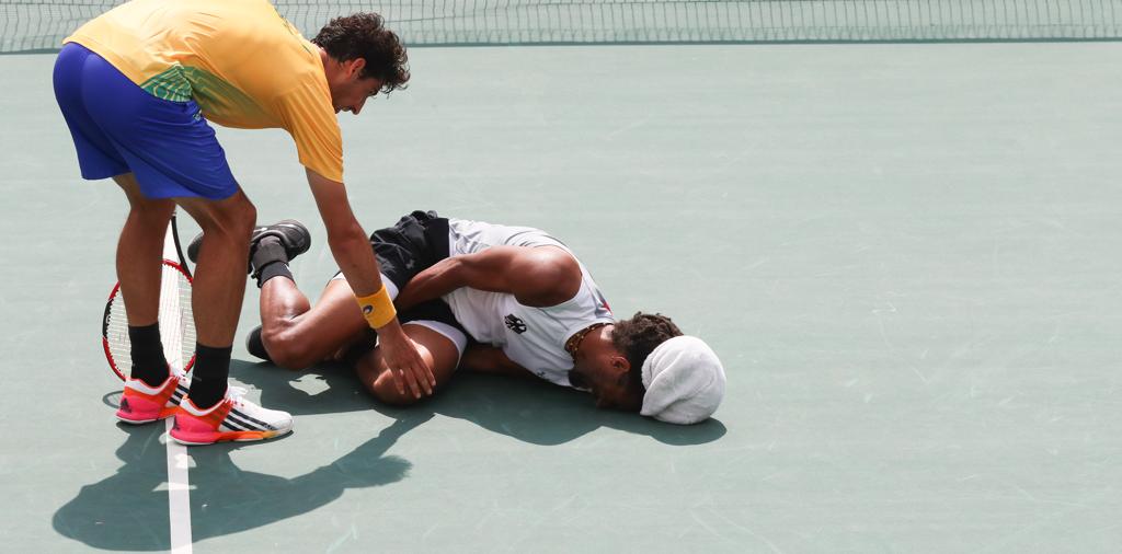 Thomaz Bellucci tenta ajudar o alemão Dustin Brown, que sentiu uma lesão no meio do duelo de estreia da Olimpíada. | Flávio Florido/Exemplus/COB