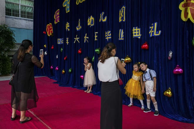 Fotos durante uma formatura de alunos de uma escola de Baishizhou. Ao todo, as cinco comunidades têm 150 mil habitantes e agora muitos deles se veem ameaçados por grandes projetos de distritos comerciais e industriais. | LAM YIK FEI/NYT