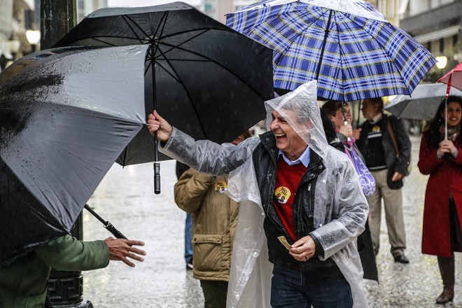 Capa de e guarda-chuva: tempo molhado não impediu o candidato do PT de pedir votos no primeiro sábado da campanha. | Jonathan Campos/Gazeta do Povo