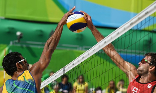 Pedro Solberg, que faz dupla com Evandro, divide bola com canadense Ben Saxton na segunda derrota da dupla brasileira na Olimpíada | YASUYOSHI CHIBA/AFP