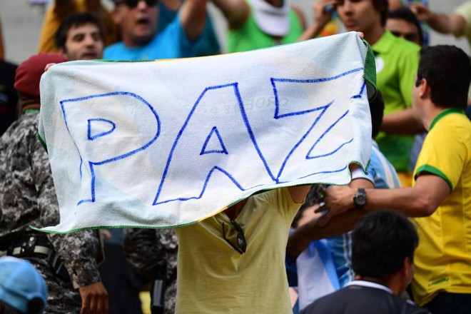 Homem segura cartaz pedindo paz no Complexo Olímpico do Tênis, após briga entre argentinos e brasileiros | MARTIN BERNETTI/AFP