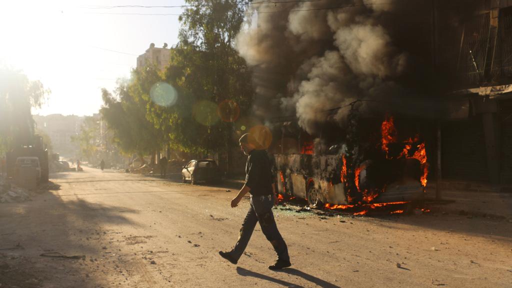 Homem caminha ao lado de veículo em chamas em Aleppo | Ameer Al Halbi/AFP