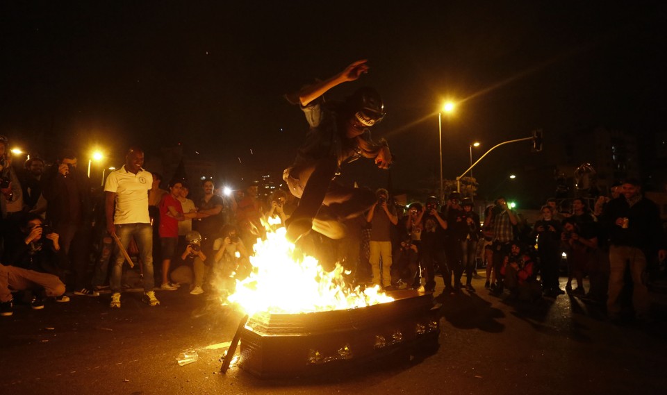 Manifestantes ao redor de caixão queimado simbolizando o governo Temer | Miguel Schincariol/AFP