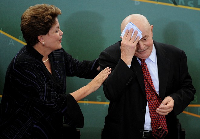 Dilma interage com o ex-presidente Lula durante cerimônia no Palácio do Planalto em janeiro de 2012. Na época Lula enfrentava tratamento para câncer de laringe. | Pedro Ladeira