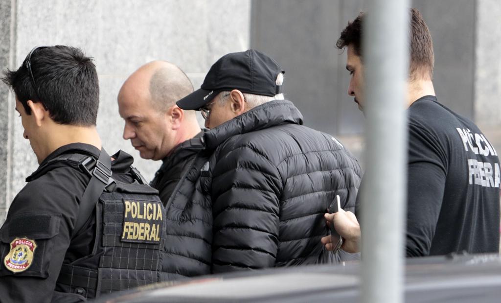 Mantega (de boné) é conduzido pelos policiais federais | MIGUEL SCHINCARIOL/AFP