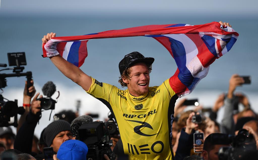 John John Florence comemora com a bandeira do Havaí o título mundial. | FRANCISCO LEONG/AFP