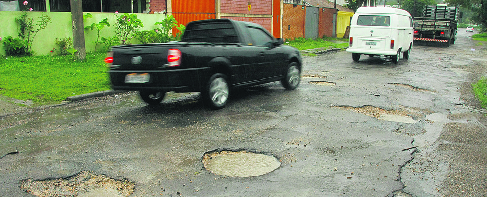 Rua esburacada em Curitiba, reflexo da redução da fatia orçamentária destinada à infraestrutura urbana em quatro anos. | Hugo Harada/Gazeta do Povo