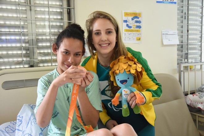 Danielle Rauen (dir.) e a paciente Renata Fernandes Batista, de 19 anos, durante visita da atleta ao Hospital Pequeno Príncipe. | Maria Fernanda Schneider /HPP