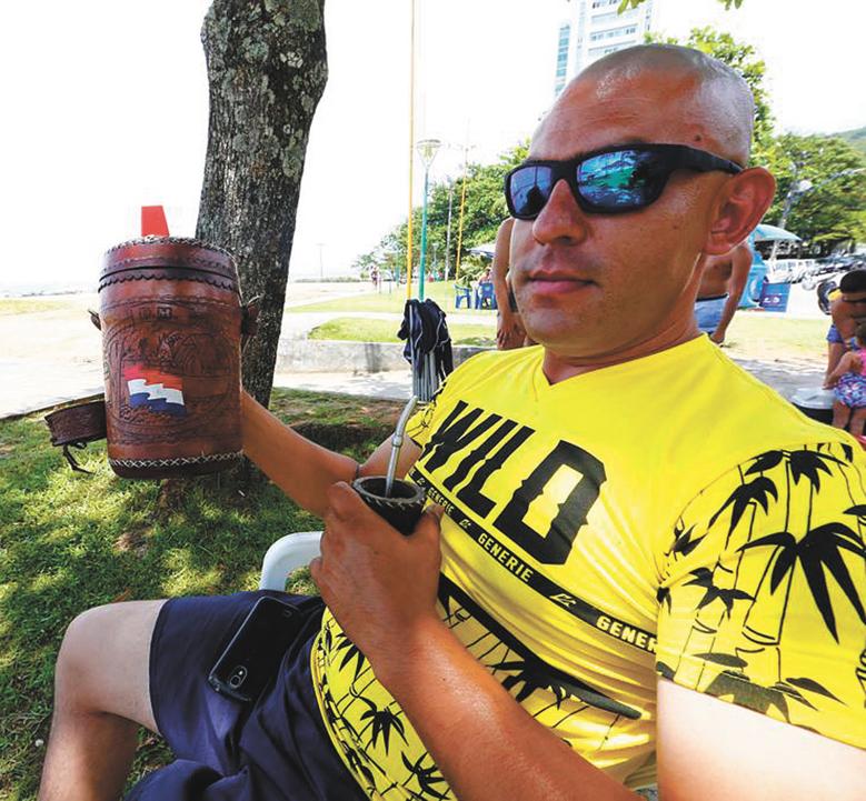 O segurança Cristian Franco, de 31 anos, aproveita a praia de Caiobá com o tererê, bebida que é símbolo do Paraguai | Lineu Filho/Tribuna do Paraná