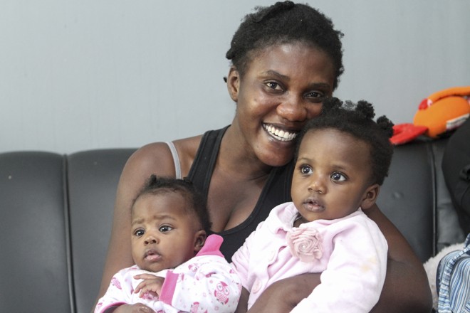A haitiana Marie Carline carrega a sobrinha Dani Letícia e a filha Thaïnouche | Rodrigo Felix Leal/Gazeta do Povo