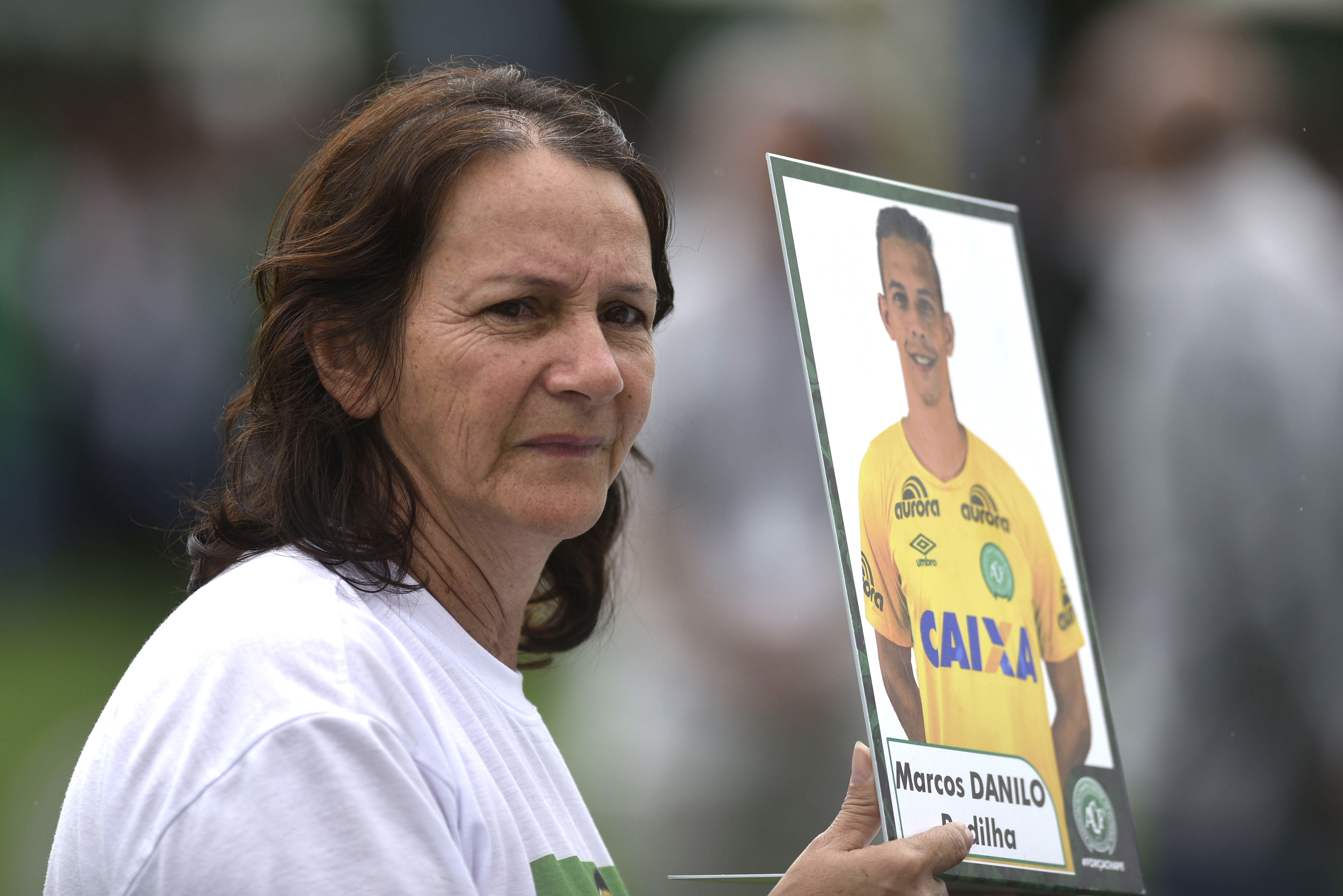 A mãe de Danilo, Ilaídes Padillha, segura uma foto do filho durante o velório coletivo em Chapecó. | Douglas Magno/AFP