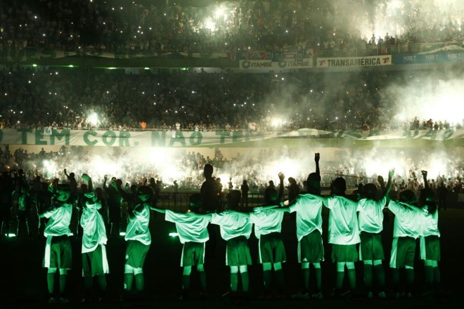 Meninos no campo assistem ao show da arquibancada no final da cerimônia. | Hugo Harada