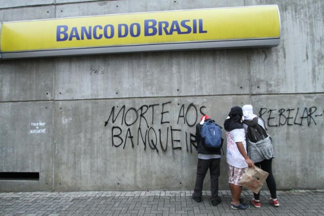 Vandalismo: Manifestantes picham portas de lojas na Rua Marechal Floriano. Ao menos três bancos tiveram suas portas estilhaçadas por pedras lançadas por pessoas que acompanham o ato. | Rodrigo Félix/Gazeta do Povo