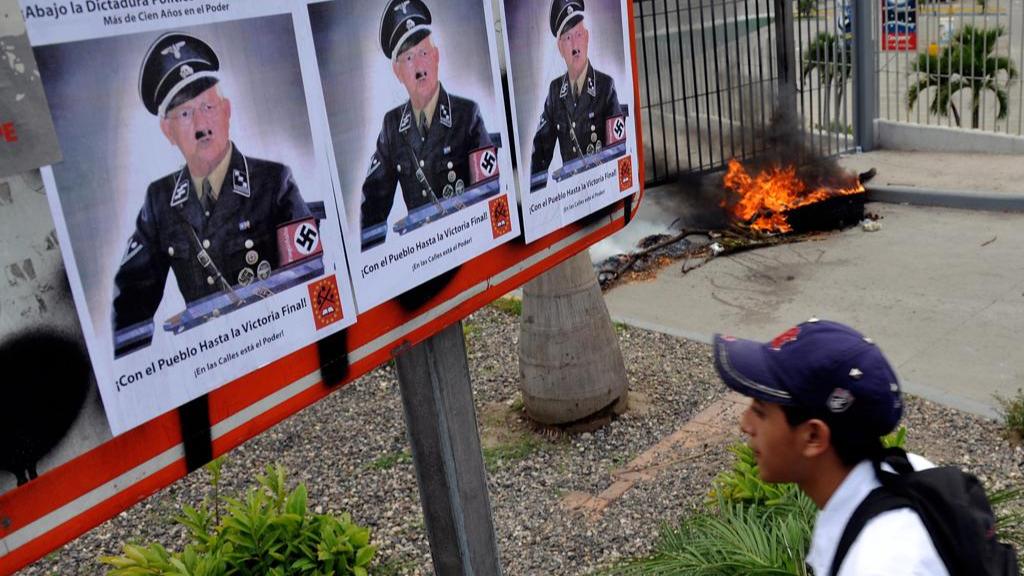 Cartaz compara o então presidente interino de Honduras, Roberto Micheletti, a Hitler, em 2009 | YURI CORTEZ /AFP