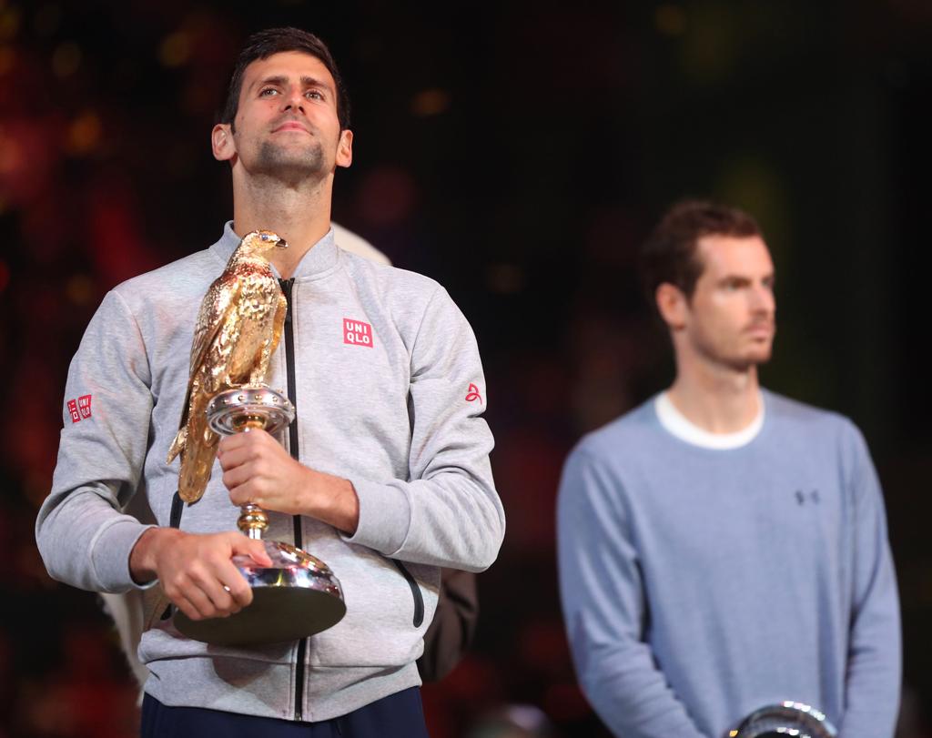 Djokovic com o troféu de campeão. Murray ao fundo. | KARIM JAAFAR/AFP