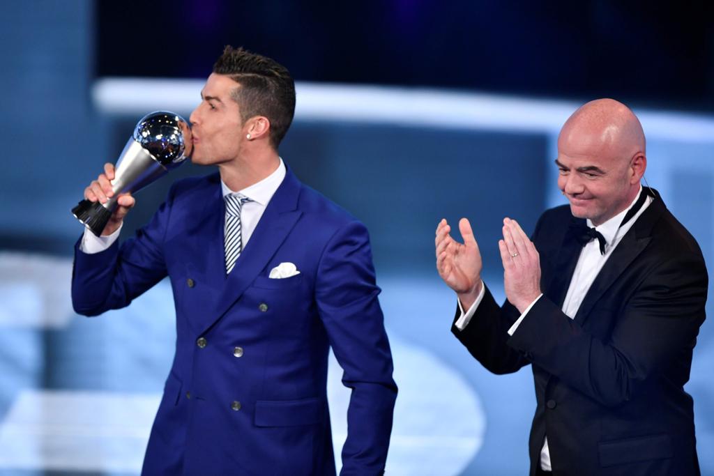 Cristiano Ronaldo beija o troféu ao lado do presidente da Fifa, Gianni Infantino. | FABRICE COFFRINI/AFP