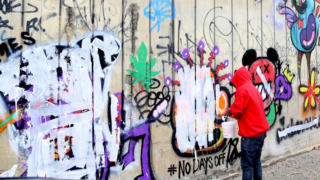 Funcionário apaga pichação feita por Justin Bieber no muro de hotel em São Conrado, no Rio de Janeiro, em 2013 | Xande Nolasco/Estadão Conteúdo