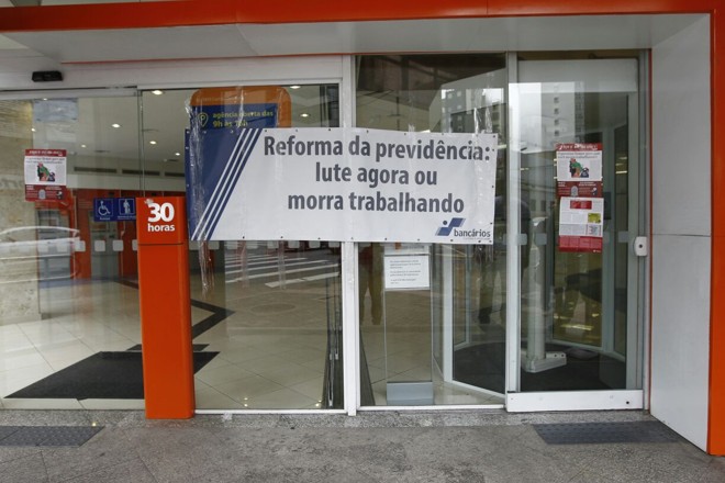 Em uma agência do banco Itaú em Curitiba, faixa do sindicato dos bancários exibe posicionamento contrário à reforma da previdência. | Jonathan Campos/Gazeta do Povo