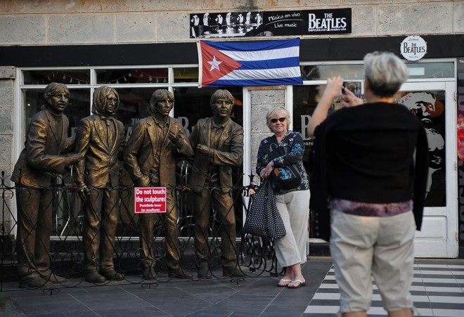 Turista posa para foto ao lado de esculturas dos Beatles, em Varadero. | Yamil Lage/AFP