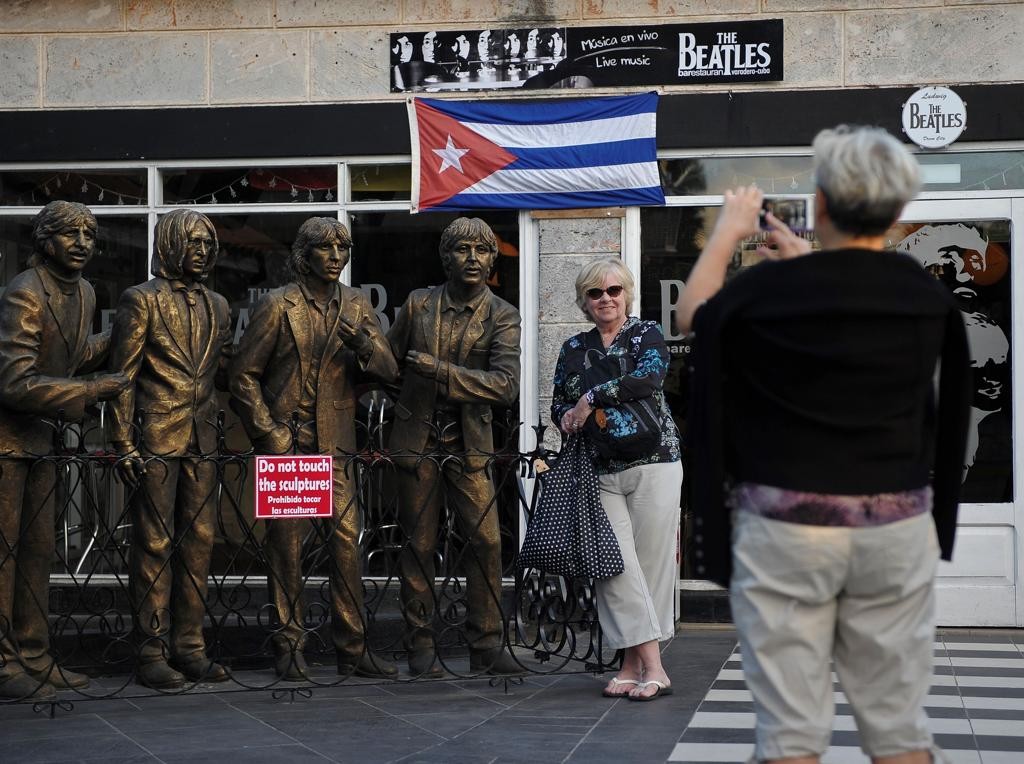 Turista posa ao lado de esculturas dos Beatles em frente de bar temático em Varadero, província de Matanza.