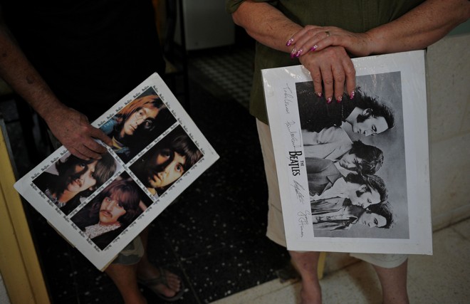 Casal segura pôsters dos Beatles. Onda de adoração à banda é maior justamente entre os cubanos acima de 60 anos. | Yamil Lage/AFP