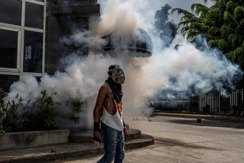 Manifestante se protege contra bombas gás lacrimogênio. | T
he Washington Post