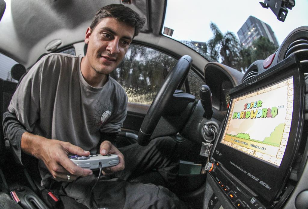 No início, o videogame era para Fernando Kania passar o tempo entre uma corrida e outra, mas os passageiros adoraram  a ideia. | Daniel Castellano/Gazeta do Povo