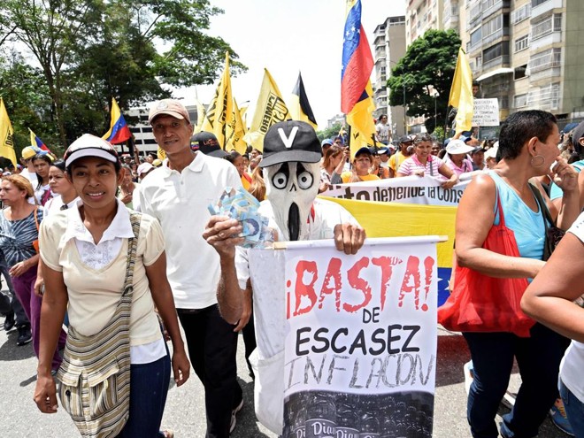 Manifestante leva cartaz pedindo o fim da escassez e da inflação | Juan Barreto/AFP