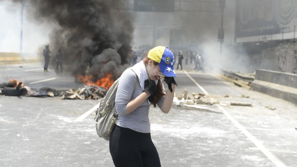 Manifestante oposicionista sofre os efeitos das bombas de gás lacrimogêneo lançadas pelos forças da ditadura de Nicolas Maduro durante protesto em Caracas. | Federico Parra/AFP