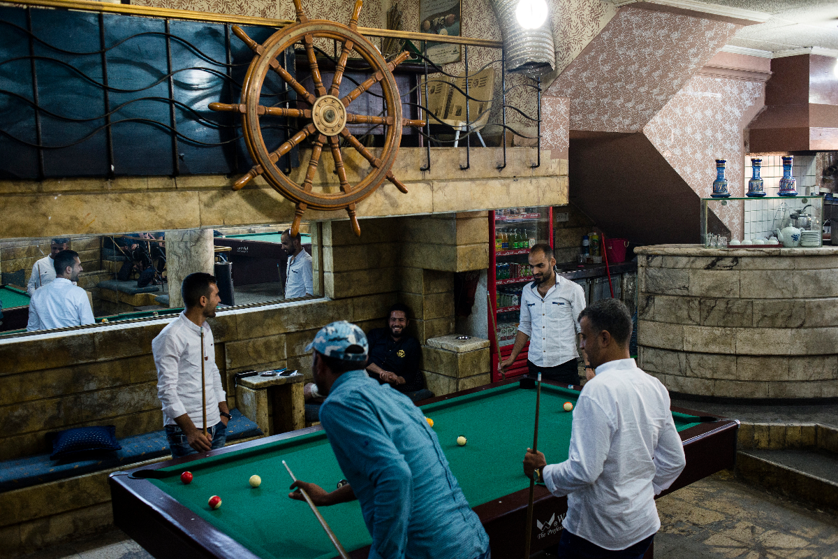Mohammed Fath (à direita) e outros moradores de Mosul jogam sinuca no Captain, casa de bilhar popular na cidade. | Alex PotterThe Washington Post