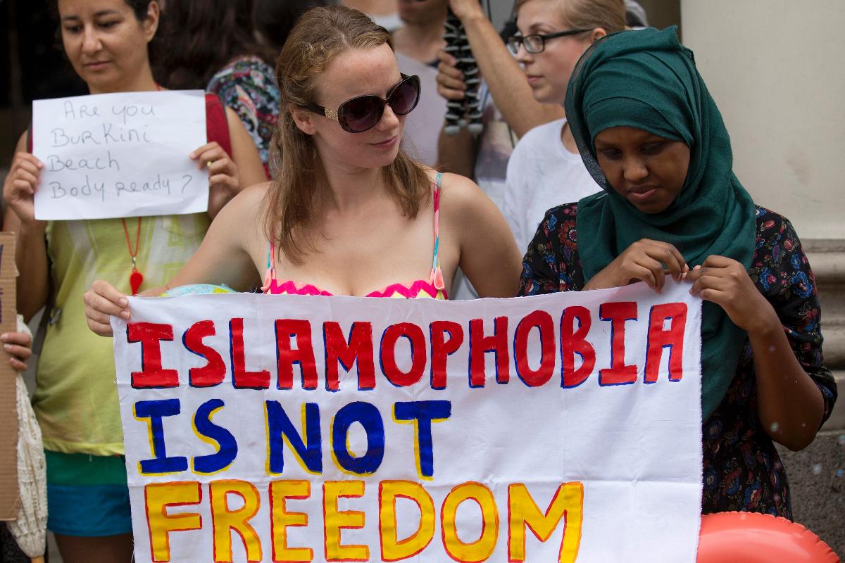 Manifestantes seguram cartaz onde se lê: “Islamofobia não é liberdade”, em frente à embaixada da França em Londres, em protesto contra a proibição dos burquínis em praias francesas | JUSTIN TALLIS/AFP