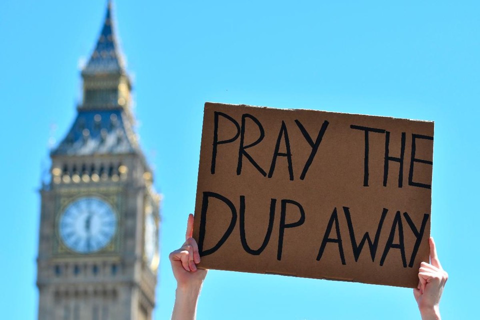 Conservadores fecham acordo com Partido Unionista Democrático Manifestantes protestam contra o Partido Democrático Unionista (DUP, na sigla em inglês), que se aliou aos Conservadores | JUSTIN TALLIS/AFP