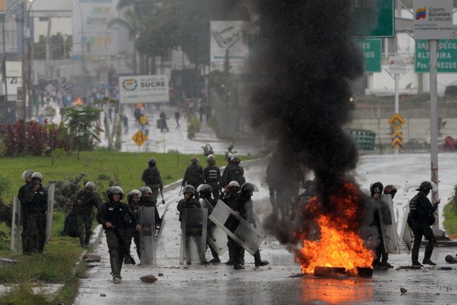 Polícia avança contra manifestantes da oposição bloqueando uma avenida durante um protesto anti-governo, em Caracas | FEDERICO PARRAAFP