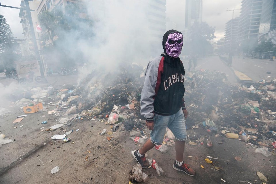 Opositor usando máscara protesta contra o governo Maduro em Caracas, capital da Venezuela | JUAN BARRETO/AFP