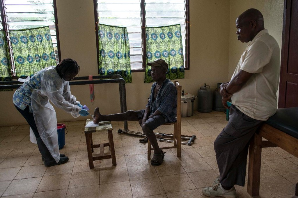 Bindu Daddah, à esquerda, cuida das feridas de John Flomo, causadas pela lepra, no leprosário de Ganta, na Libéria: em todo o mundo, o número de casos de lepra caiu 97% desde 1985