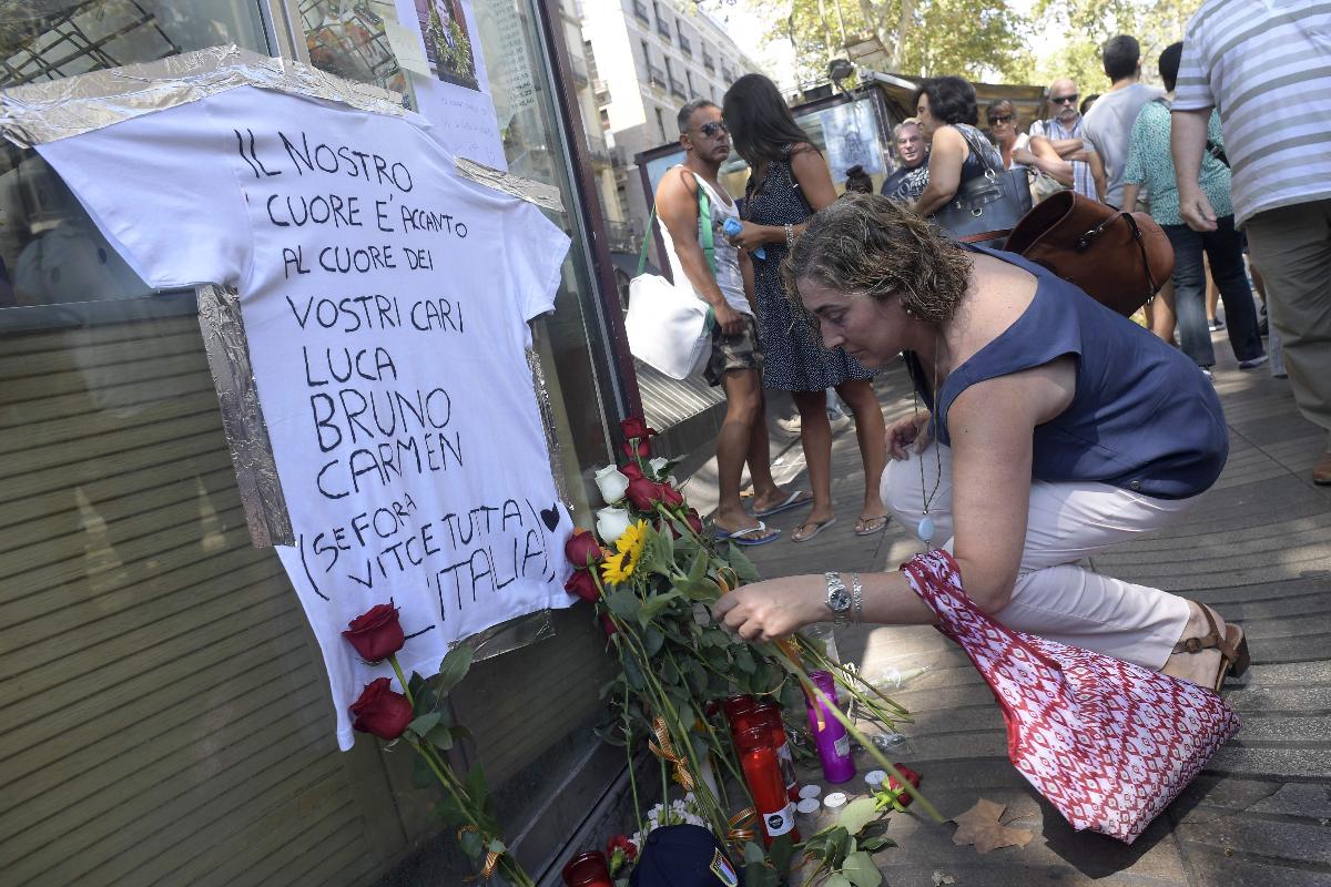 Mulher coloca uma flor ao prestar homenagem às vítimas italianas em Las Ramblas, Barcelona, em 21 de agosto de 2017, quatro dias após os ataques de Barcelona e Cambrils, nos quais 15 pessoas foram mortas. | JAVIER SORIANO/AFP