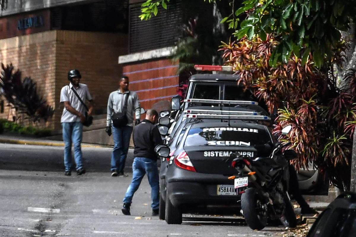 Membros do Serviço Bolivariano de Inteligência Nacional  (SEBIN) aguardam do lado de fora da casa da ex-procuradora geral Luisa Ortega, em Caracas | JUAN BARRETO/
AFP