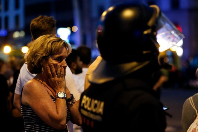 Uma mulher gesticula enquanto é escoltada por policiais para fora de uma área isolada depois que uma van passou por cima de uma multidão, matando 13 pessoas e ferindo mais de 80 em Rambla, Barcelona, rua mais popular da cidade | PAU BARRENA/AFP