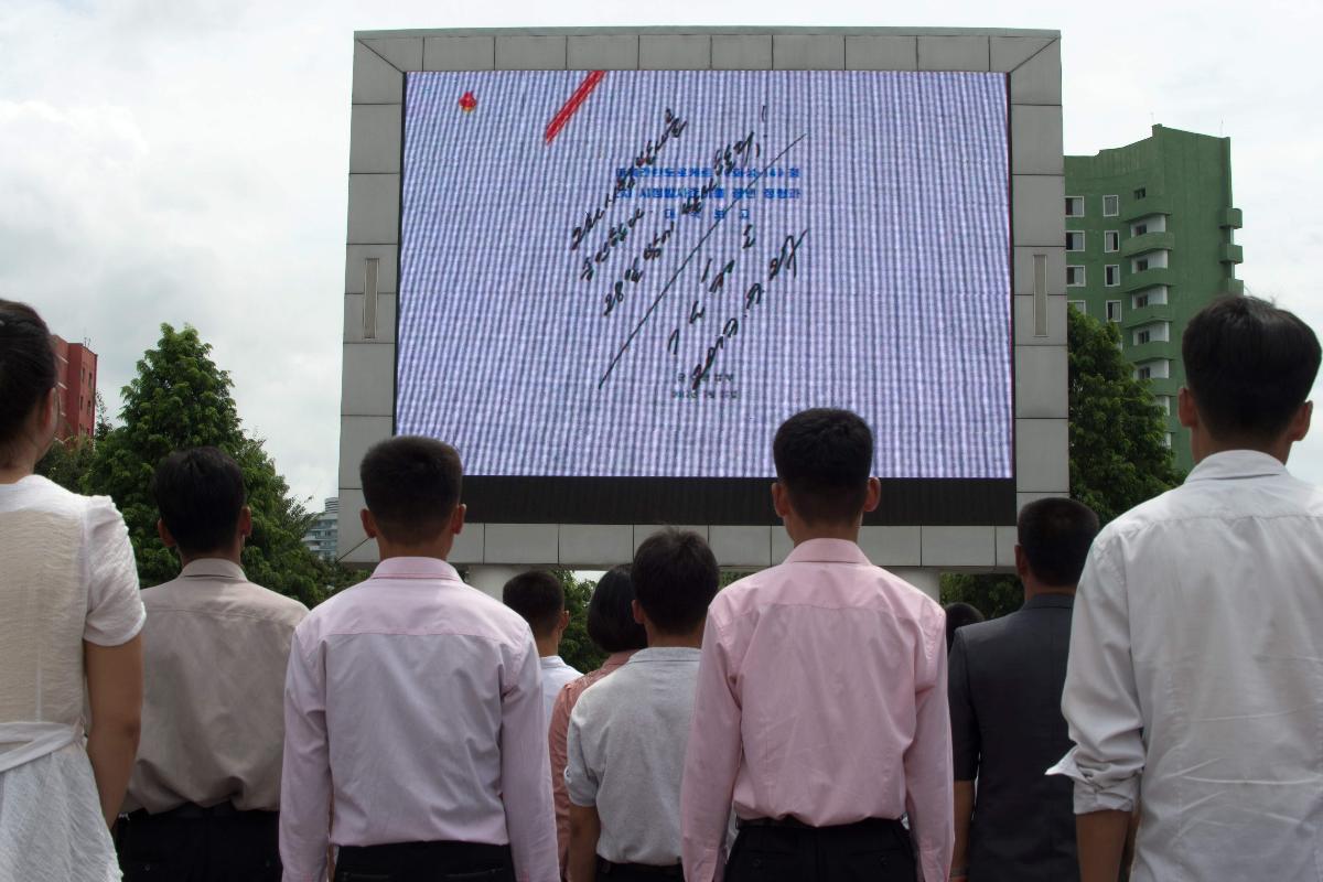 Norte-coreanos assistem a cobertura do lançamento de míssil em telão público, em Pyongyang | KIM WON-JIN/AFP